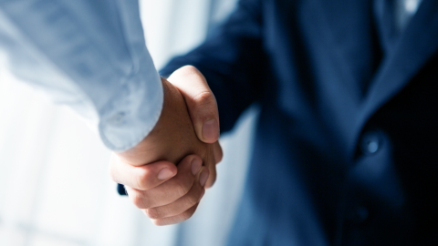 Two people shaking hands in office attire.